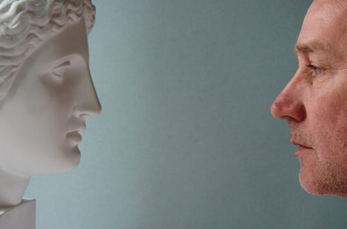 Due volti di profilo, a sinistra quello di una statua di donna, a destra quello di un uomo