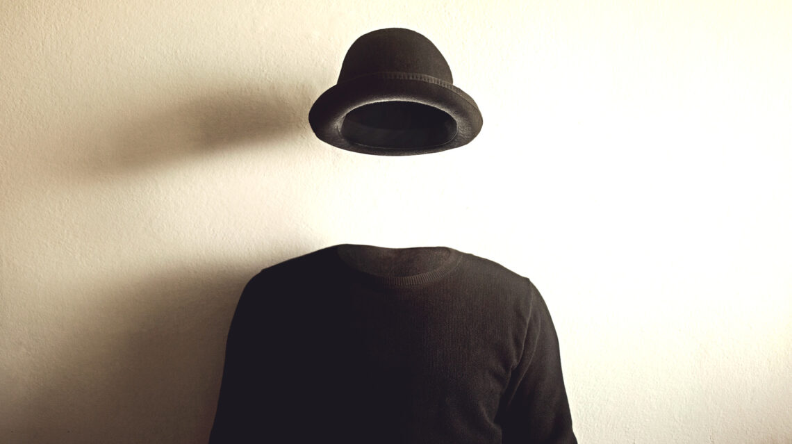 Fotografia che ritrae un maglione nero e un cappello nero che fluttua nell'aria sopra lo stesso, davanti a un muro bianco su cui si proiettano le ombre del maglione e del cappello. Sembra di osservare un uomo invisibile.