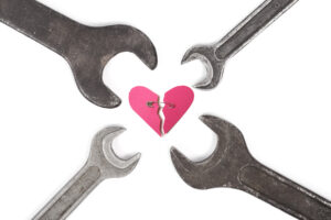 Una fotografia che ritrae, al centro, un cuore stilizzato, rosa, spezzato; le due parti sono tenute vicine da una spilla da balia; disposte intorno al cuore, con la parte che abitualmente si usa per girare i bulloni vicina allo stesso, ci sono quattro chiavi inglesi di diverse misure.