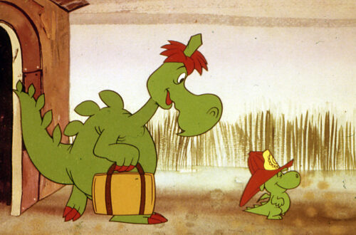 Un fotogramma dalla serie a cartoni animati "Grisù il draghetto": a destra c'è Grisù, un piccolo draghetto verde, di profilo, che cammina verso destra orgoglioso e contento con un casco da pompiere in testa; alla sua sinistra, dietro di lui, lo segue Fumè, suo padre, un grosso drago, con una valigia nella zampa anteriore destra.