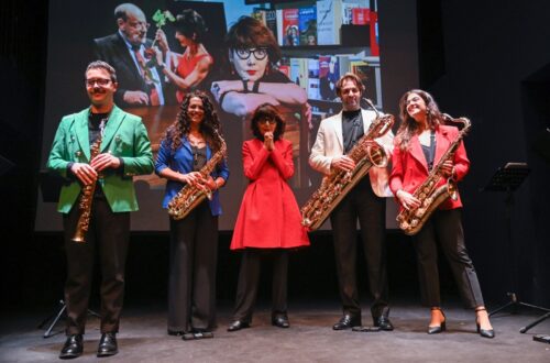 Una foto che ritrae, sul palco del Teatro Franco Parenti, al centro, vestita di rosso, Elisabetta Sgarbi, attorniata dagli artisti del Rhapsody Saxophone Quartet - Mattia Catarinozzi, sax soprano, Marina Notaro, sax contralto, Marianna Di Ruvo, sax tenore e Luis Lanzarini, sax baritono - alla premiazione del “Matto dell’anno” 2023.