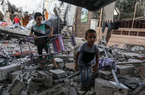 Una fotografia che ritrae bambini palestinesi tra le macerie di un edificio.