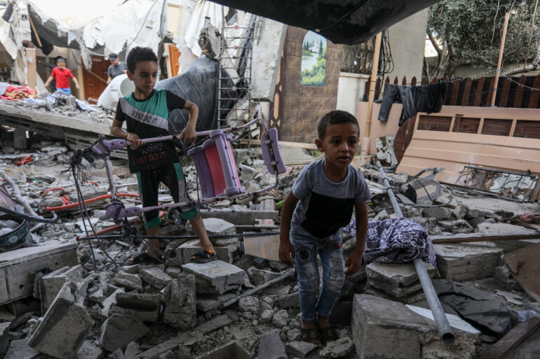 Una fotografia che ritrae bambini palestinesi tra le macerie di un edificio.