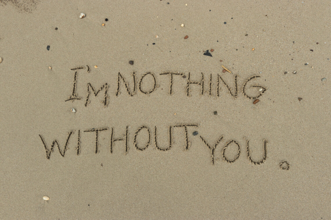 Una fotografia che ritrae da vicino il bagnasciuga di una spiaggia di sabbia con piccole conchiglie, rametti e sassolini. Al centro c'è una scritta tracciata nella sabbia con un dito, "I'm nothing without you" ("Senza te sono niente"), e destinata a essere cancellata dalla prossima onda abbastanza lunga.