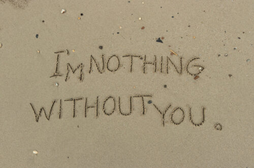 Una fotografia che ritrae da vicino il bagnasciuga di una spiaggia di sabbia con piccole conchiglie, rametti e sassolini. Al centro c'è una scritta tracciata nella sabbia con un dito, "I'm nothing without you" ("Senza te sono niente"), e destinata a essere cancellata dalla prossima onda abbastanza lunga.