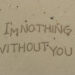 Una fotografia che ritrae da vicino il bagnasciuga di una spiaggia di sabbia con piccole conchiglie, rametti e sassolini. Al centro c'è una scritta tracciata nella sabbia con un dito, "I'm nothing without you" ("Senza te sono niente"), e destinata a essere cancellata dalla prossima onda abbastanza lunga.