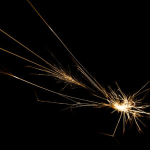 Una fotografia che ritrae, su sfondo completamente nero, una gran quantità di scintille che si dipartono da un punto in basso a destra nella foto e schizzano intorno, in particolare verso l'angolo in alto a sinistra, lasciando tante scie luminose.