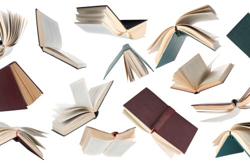 Una composizione fotografica che mostra tanti libri aperti che paiono svolazzare su uno sfondo bianco.