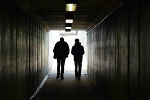 Una foto a colori, in formato orizzontale, che ritrae due persone che camminano verso la fine di un tunnel.