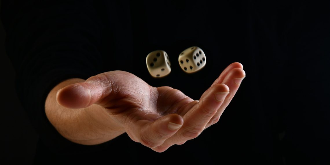 Una mano femminile su sfondo nero che lancia due dadi verso l'alto.