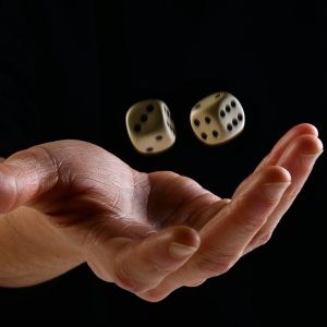 Una mano femminile su sfondo nero che lancia due dadi verso l'alto.