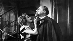 Particolare di un fotogramma in bianco e nero dal film “L’angelo azzurro”, di Josef von Sternberg, 1930. C’è Marlene Dietrich, nei panni di Lola Lola, che sorridendo punta un dito sotto il mento di Emil Jannings, nei panni del professor Immanuel Rath, il quale ha il mento sollevato e la testa leggermente inclinata all’indietro.