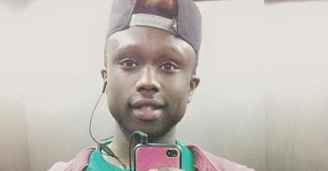 Una foto (presumibilmente un “selfie” allo specchio) che ritrae Moussa Sangare sorridente con un cellulare in mano e un auricolare delle cuffie “in-ear” collegate allo stesso nell’orecchio destro.