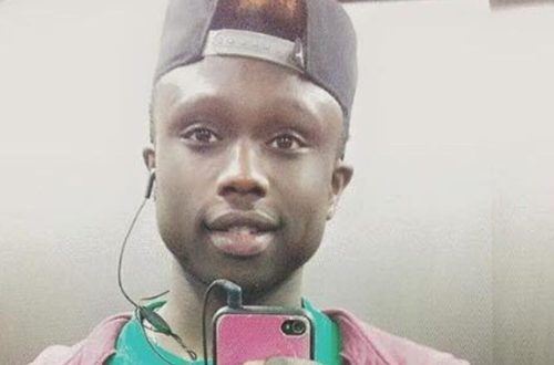 Una foto (presumibilmente un “selfie” allo specchio) che ritrae Moussa Sangare sorridente con un cellulare in mano e un auricolare delle cuffie “in-ear” collegate allo stesso nell’orecchio destro.