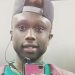 Una foto (presumibilmente un “selfie” allo specchio) che ritrae Moussa Sangare sorridente con un cellulare in mano e un auricolare delle cuffie “in-ear” collegate allo stesso nell’orecchio destro.