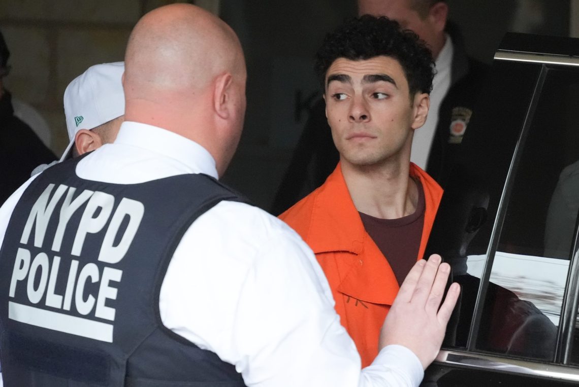 Una foto che ritrae Luigi Mangione mentre viene caricato su una macchina da alcuni agenti della polizia di New York.