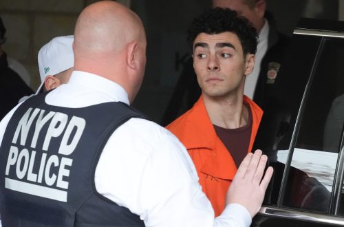 Una foto che ritrae Luigi Mangione mentre viene caricato su una macchina da alcuni agenti della polizia di New York.