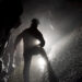 Una foto a colori, in formato orizzontale, che ritrae al centro di un cunicolo sotterraneo uno speleologo di spalle che illumina la strada davanti a sé con una torcia.