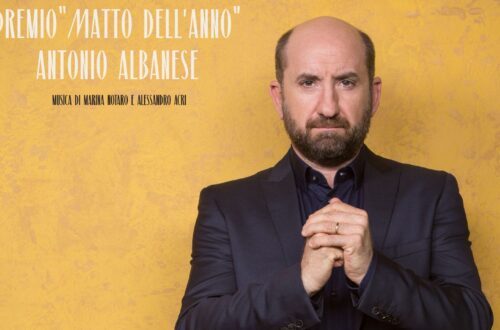 Locandina della settima edizione del premio "Matto dell'anno". C'è una foto a colori, in formato verticale, che ritrae Antonio Albanese in piedi davanti a un muro intonacato di color giallo ocra. Albanese è ritratto dalle anche in su, indossa un completo nero, ha le mani unite a pugno tenute davanti al petto, un'espressione seria di gratitudine e combattività sul volto. In alto a sinistra c'è una scritta bianca: «7^ edizione - premio "Matto dell'anno" - Antonio Albanese»; sotto, in piccolo e in nero: «Musica di Marina Notaro e Alessandro Acri». Nell'angolo in basso a sinistra dell'inquadratura ci sono due loghi affiancati: "MAO" e "Fondazione Lighea onlus", quest'ultimo con la grafica in azzurro che raffigura la sirena Lighea di profilo con le mani alzate davanti al viso, come se cantasse a gran voce, sopra la scritta già citata, in nero.
