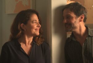 Un fotogramma dal film "La mia amica Eva" di Cesc Gay. Una donna e un uomo si guardano con affetto e gioia, appoggiati entrambi allo stipite di un muro, faccia a faccia, a distanza di circa mezzo metro, lei a sinistra, lui a destra.