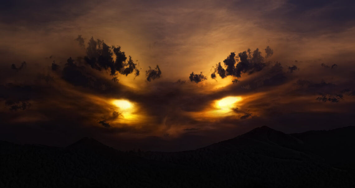 Una foto a colori che ritrae un tramonto. La luce e la disposizione delle nubi sembrano dar forma a due occhi cattivi nel cielo.