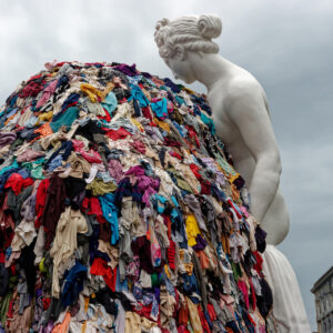 Napoli, Italia - 30 settembre 2023: La monumentale installazione artistica “Venere degli stracci” dell’artista contemporaneo Michelangelo Pistoletto è esposta all’aperto in città. Una classica scultura bianca raffigurante la dea romana si affaccia su un’enorme pila di indumenti colorati scartati. Questo iconico capolavoro dell’Arte Povera contrappone visivamente l’antica bellezza classica al consumismo e agli sprechi della moda fast fashion moderna, offrendo una potente riflessione culturale e sociale ai turisti di tutto il mondo e agli amanti dell’arte.
