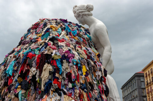 Napoli, Italia - 30 settembre 2023: La monumentale installazione artistica “Venere degli stracci” dell’artista contemporaneo Michelangelo Pistoletto è esposta all’aperto in città. Una classica scultura bianca raffigurante la dea romana si affaccia su un’enorme pila di indumenti colorati scartati. Questo iconico capolavoro dell’Arte Povera contrappone visivamente l’antica bellezza classica al consumismo e agli sprechi della moda fast fashion moderna, offrendo una potente riflessione culturale e sociale ai turisti di tutto il mondo e agli amanti dell’arte.