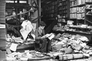 Una famosa foto che ritrae un ragazzo che legge un libro seduto tra le rovine di una libreria londinese durante la campagna del blitz tedesco nel 1940.