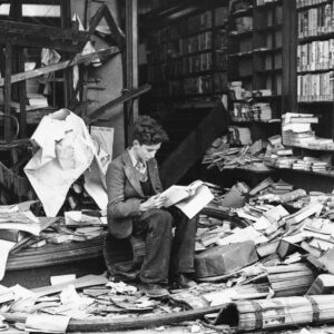Una famosa foto che ritrae un ragazzo che legge un libro seduto tra le rovine di una libreria londinese durante la campagna del blitz tedesco nel 1940.